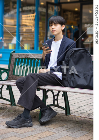 ベンチに座ってスマホを見る20代男性のビジネスマン 131545261