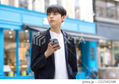 街中でスマホを持って立つ20代男性のビジネスマン 街中でスマホを持って立つ20代男性のビジネスマン 131545296