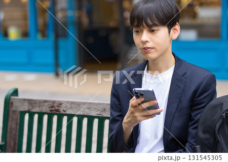 ベンチに座ってスマホを見る20代男性のビジネスマン ベンチに座ってスマホを見る20代男性のビジネスマン 131545305