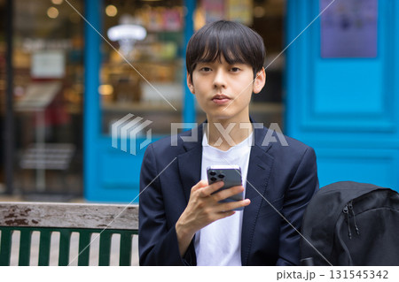 ベンチに座ってスマホを見る20代男性のビジネスマン ベンチに座ってスマホを見る20代男性のビジネスマン 131545342