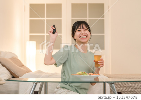 夕食に晩酌しながらテレビを見ながら笑う若いアジア人女性 131547678