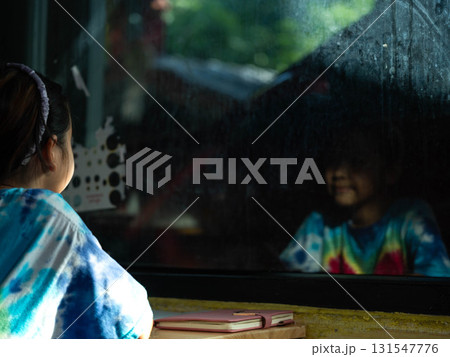 Girl looking through window with reflection of herself Girl looking through window with reflection of herself 131547776