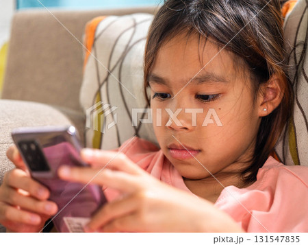 A young girl lying on a sofa and using a smartphone.  131547835