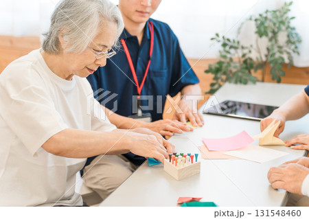 リハビリでシリンダーペグを使い手指機能訓練をするシニアと作業療法士の男女 131548460