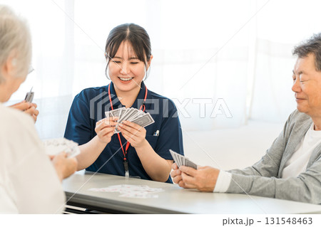 グループホーム,老人ホームでトランプをする高齢者と介護士の女性スタッフ 131548463