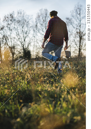 Lumberjack walking through field with axe and firewood 131550443