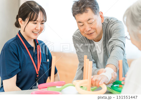 リハビリをするシニア男性と介護士,作業療法士の女性スタッフ リハビリをするシニア男性と介護士,作業療法士の女性スタッフ 131551447