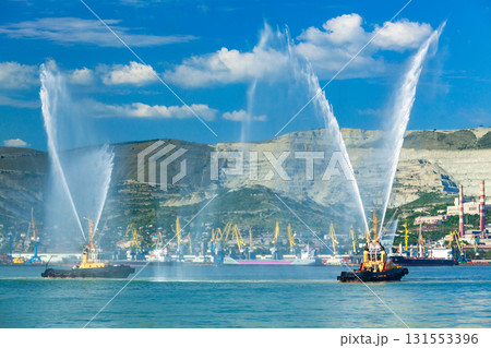 Floating tug boats are spraying jets of water, demonstrating theis firefighting water cannons Floating tug boats are spraying jets of water, demonstrating theis firefighting water cannons 131553396