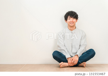 白い壁のリビングにあぐらで座る若いアジア人男性 白い壁のリビングにあぐらで座る若いアジア人男性 131553467