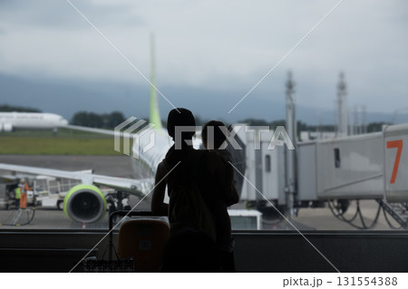 夏の終わりの空港でフライトを心待ちにしている母と子のシルエット 夏の終わりの空港でフライトを心待ちにしている母と子のシルエット 131554388