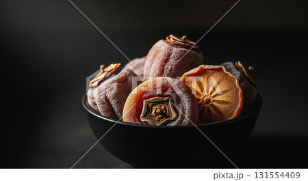Frosted Dried Persimmons in Black Bowl with Dark Background 131554409