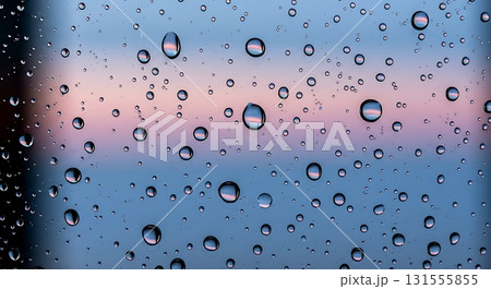 Stunning macro view captures delicate water droplets on glass reflecting a soft pastel sunset, creating a serene and tranquil atmosphere perfect for backgrounds. 131555855