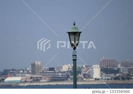 青空と海と街並みをバックにおしゃれな街灯にピントを合わせ撮影した風景 131556560
