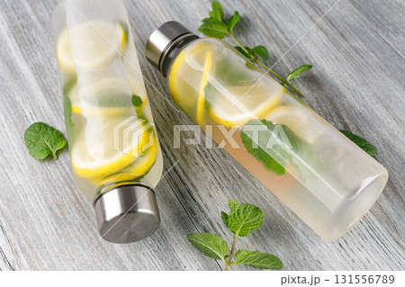 Two bottles of refreshing lemon and mint infused water resting on a wooden table 131556789