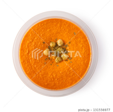 Bowl of red pepper hummus garnished with chickpeas and parsley 131556977