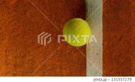 Freeze Motion Detail Shot of Tennis Ball Hitting a Clay Court 131557179