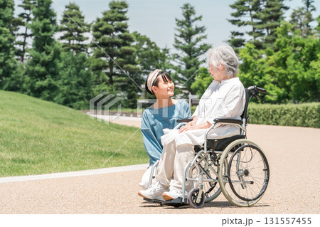 車椅子に乗るおばあちゃんをお見舞いに来た孫娘 131557455