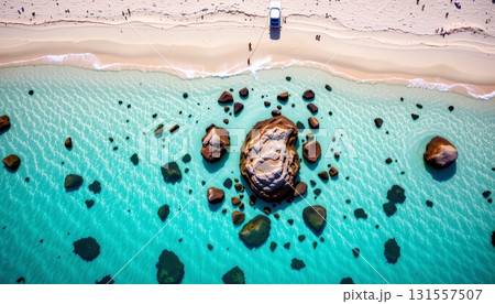 An expansive beach scene with turquoise waters, a rocky shoreline, and multiple people enjoying the sunny day. 131557507