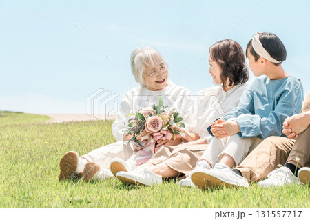 青空の見える公園・丘に座る家族・親子・三世代家族(父親・母親・娘・祖母・祖父) 青空の見える公園・丘に座る家族・親子・三世代家族(父親・母親・娘・祖母・祖父) 131557717