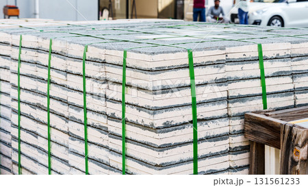 Pallets with stacked gray paving slabs selective focus Stack of paving slabs in warehouse road repair or finished tile sale space for text. High quality photo 131561233