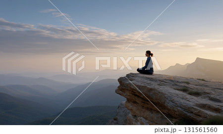 崖の上で瞑想する女性と明け方の山々 131561560