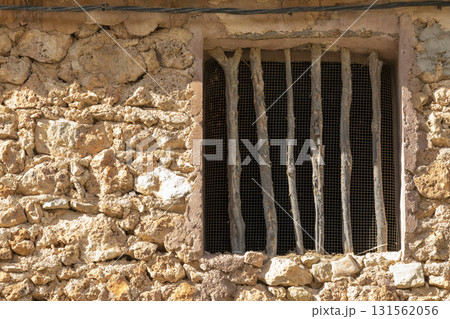 A window with bars on it is shown in a stone building 131562056