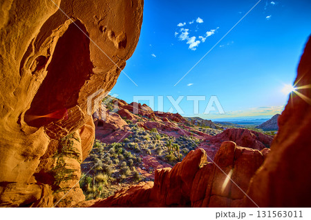 Red Sandstone Arch Formation and Desert Landscape with Sunburst 131563011