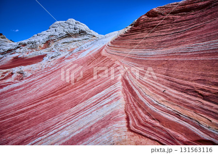 Vivid Striated Sandstone and White Pocket Rock Formation under Clear Blue Sky Vivid Striated Sandstone and White Pocket Rock Formation under Clear Blue Sky 131563116
