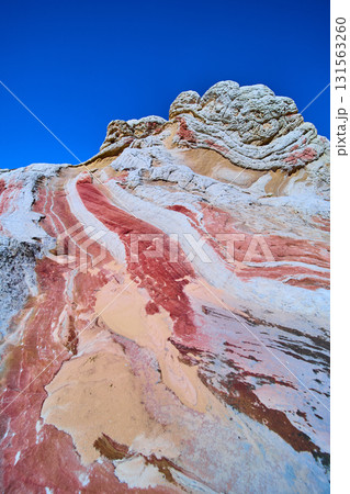 Colorful Swirling Sandstone Layers and Eroded Outcrop Under Blue Sky White Pocket 131563260