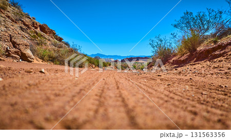 Desert Trail Ground Level with Red Earth and Distant Mountains 131563356