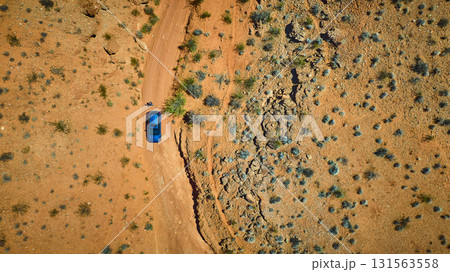 Aerial Desert Road and Blue Vehicle in Rugged Nevada Landscape Aerial Desert Road and Blue Vehicle in Rugged Nevada Landscape 131563558