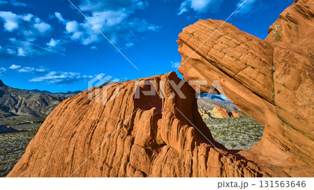 Red Sandstone Arch Formation and Desert Landscape Under Vibrant Blue Sky 131563646
