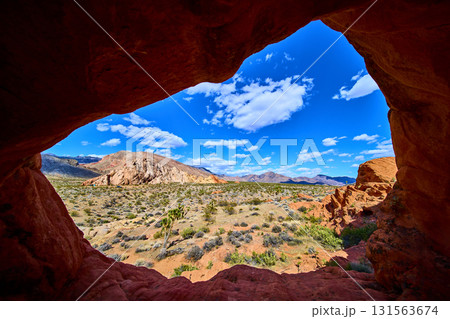 Natural Arch Formation Framing Desert Landscape Under Blue Sky 131563674