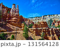 Bryce Canyon Hoodoos and Hiker on Peekaboo Loop Trail Under Blue Sky 131564128