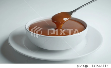 Caramel cream sauce for topping sweet snack on white mug and spoon Caramel cream sauce for topping sweet snack on white mug and spoon 131566117