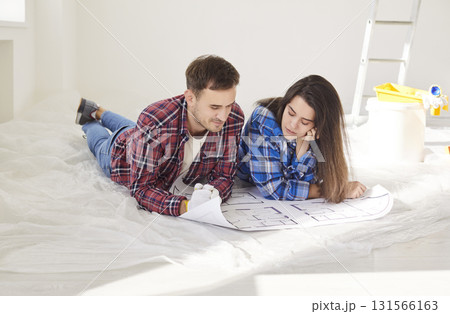 Happy young married couple amuse looking at repair project on paper blueprints, planning work 131566163