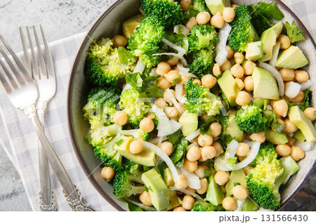 green salad of broccoli, chickpeas, avocado, onion, and parsley with lemon oil, close-up in a bowl. Horizontal top view 131566430
