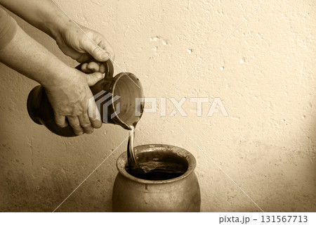 A hand holds a clay jar and pours water A hand holds a clay jar and pours water 131567713