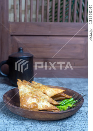 Crispy Martabak Tahu or Indonesian tofu filled fritters on a wooden plate, served with fresh green chilies, perfect for a snack or appetizer. Crispy Martabak Tahu or Indonesian tofu filled fritters on a wooden plate, served with fresh green chilies, perfect for a snack or appetizer. 131568149