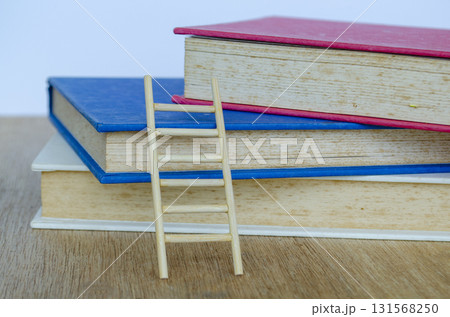 Books on a wooden desk with wooden ladder under natural daylight emphasizing peaceful study time. Books on a wooden desk with wooden ladder under natural daylight emphasizing peaceful study time. 131568250