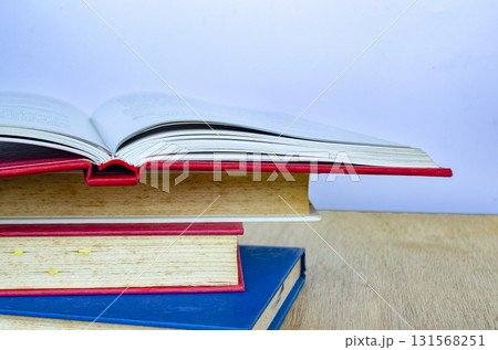 A dynamic arrangement of books stacked and one half open with pages mid turn creating a motion effect. 131568251