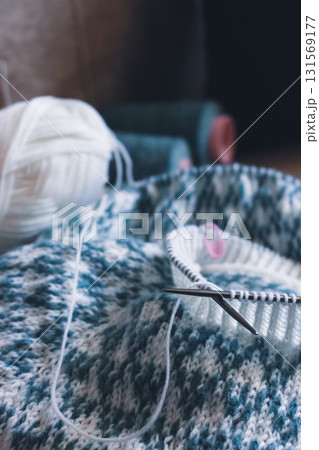 Norwegian knitted pattern. Knitting needles and beautiful knitting pattern. White and azure knitted pattern. Knitting hobby. Knitwear concept. Spot sweater process.  131569177