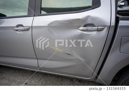 Side door impact with visible dent and scratch marks on silver vehicle - digital vehicle damage assessment for insurance analytics 131569355