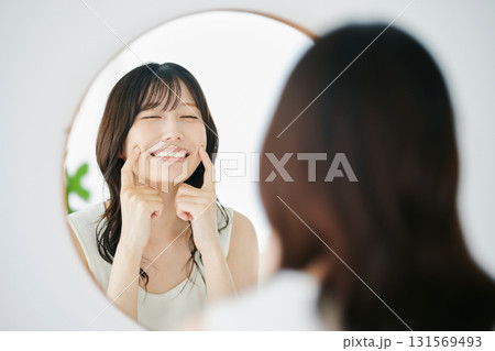 鏡で肌の状態を確認する笑顔の女性 131569493