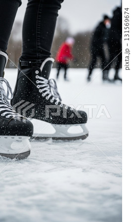 Close-up of ice skates on outdoor rink with people blurred in background focusing on winter activity 131569674