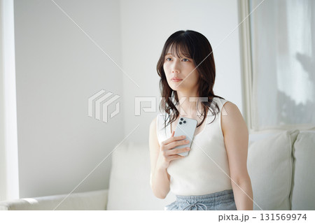 ソファに座ってスマホを持つ女性 ソファに座ってスマホを持つ女性 131569974