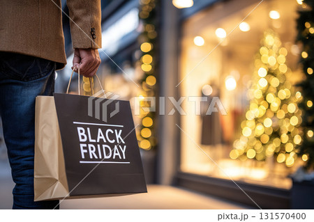 Black Friday discount and sales concept. A man holds a craft bag with the words Black Friday in front of a store window. Black Friday discount and sales concept. A man holds a craft bag with the words Black Friday in front of a store window. 131570400
