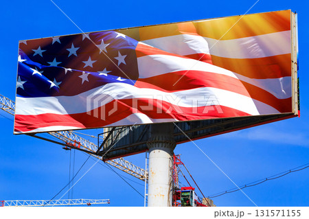 Large billboard with the USA american flag with blue sky behind it. Large billboard with the USA american flag with blue sky behind it. 131571155