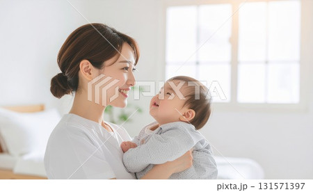 赤ちゃんと顔を見つめる若い母親　白色基調の柔らかな日が差す背景 131571397