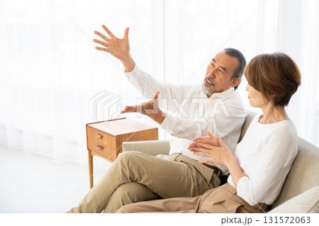 ソファでくつろぎながら会話をするシニア夫婦 131572063